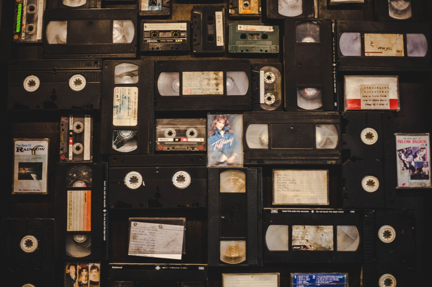 A wall of assorted VHS tapes and cassettes laid out edge to edge
