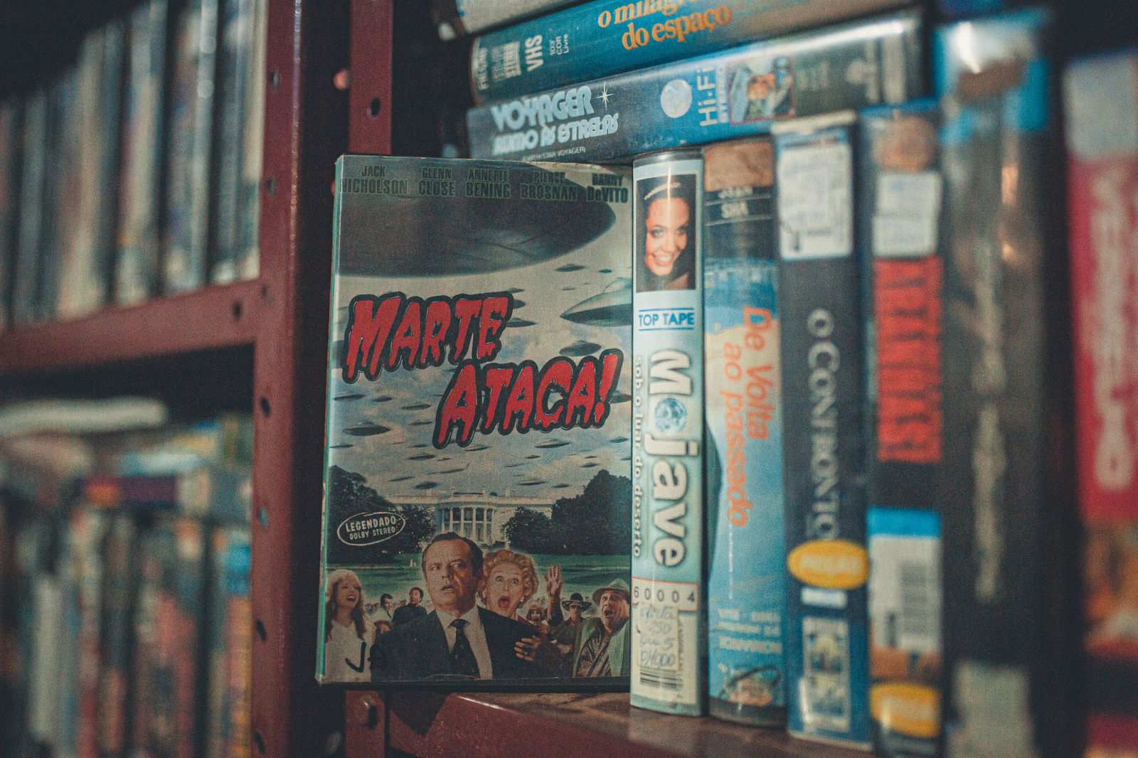 Vintage VHS boxes with classic movie titles lined up on a wooden shelf