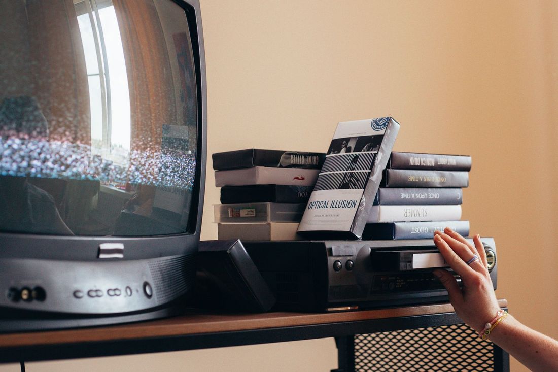 A vintage television and a stack of tapes on a sideboard