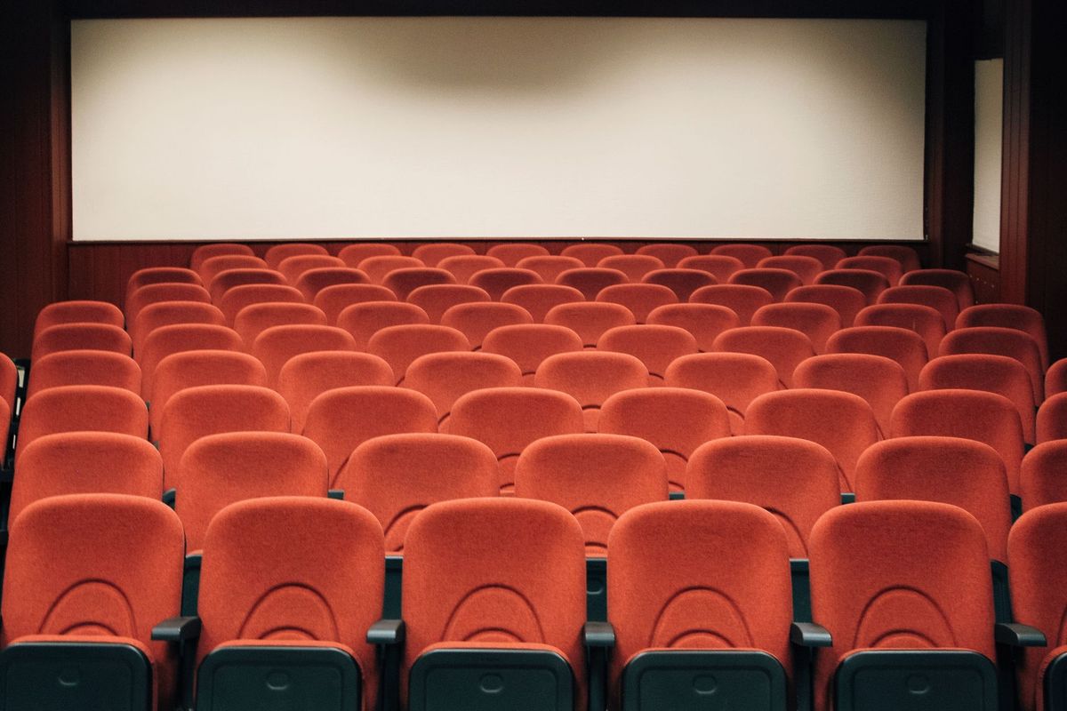 Rows of red cinema seats facing a blank screen